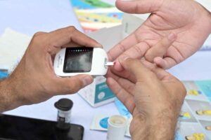 Een zorgverlener voert tijdens een bijeenkomst ter gelegenheid van Wereld Diabetes Dag een bloedsuikertest uit om bewustwording te vergroten.